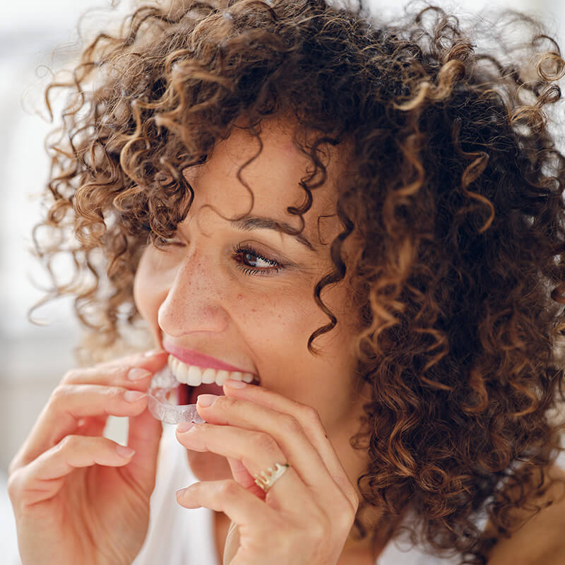 Woman in Bed in the Morning Using Clear Teeth Aligners