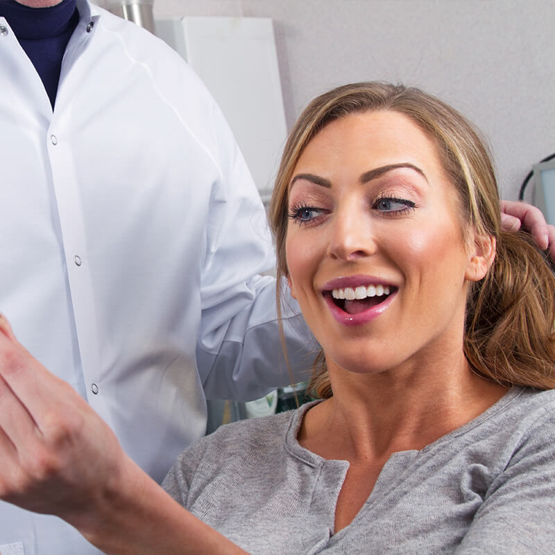 Satisfied dental patient looking at her teeth