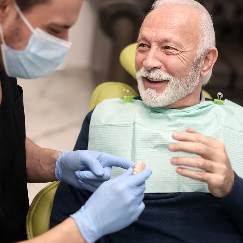 Senior man at a dentist's office, looking at dentures.